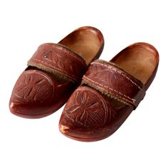 This is a pair of vintage folk art wooden clogs with leather strap.  The reddish brown wood shoes feature carved detailing across the foot and a tooled leather strap with woolly lining.   Insole Length:  7" Insole Width:  2.5" Heel:  1/2" Traditional Brown Slip-on Clogs, Traditional Brown Mules With Rubber Sole, Western Style Brown Leather Clogs, Western Brown Leather Clogs, Vintage Brown Mules With Leather Sole, Western Leather Clogs With Round Toe, Brown Wood Slip-on Clogs, Traditional Brown Mules With Leather Sole, Traditional Closed Toe Clogs