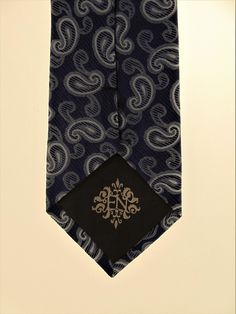 "Mens 100% silk blue paisley necktie. This Blue paisley tie features a navy background with blue ourlined with off white paisley pattern. Handmade from 100% silk, this special collection features a .75\" Eds Neckties logo at the bottom right front corner of every tie and a larger logo located on the tipping (Back of the tie). The label features the collection name (Nathaniel Alexandria) Named after my son Nathaniel and my daughter Alexandria. Expertly hand-made from 100% silk you can select your Formal Patterned Paisley Suit And Tie Accessories, Elegant Black Tie Suit Accessories With Paisley Print, Blue Paisley Print Suit And Tie Accessories, Blue Paisley Print Tie For Black Tie Events, Blue Paisley Print Ties For Black Tie Events, Elegant Semi-formal Neckwear With Paisley Print, Blue Paisley Print Ties For Black Tie Occasion, Blue Paisley Print Ties For Business, Blue Paisley Print Tie