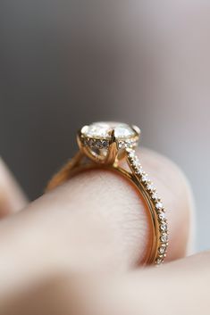 a close up of a person's hand holding a diamond ring