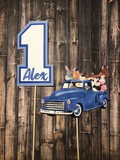 an old blue truck with farm animals on it is next to a one - sided sign