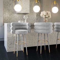 three stools in front of a bar with flowers on the counter and lights hanging from the ceiling