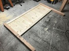 an unfinished bed frame in the process of being made with plywood and other woodworking tools