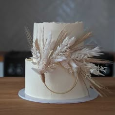 a close up of a cake on a wooden table with white frosting and feathers