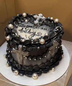 a black and white decorated cake on top of a cardboard box with silver pearls around the edges