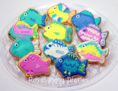 decorated cookies in the shape of fish on a clear plate