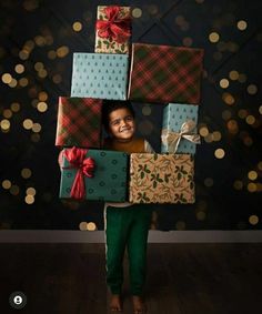 a young boy is holding presents in front of his face and smiling at the camera