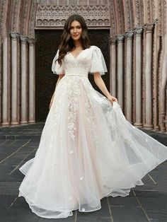 a woman in a wedding dress standing on a stone floor with her arms behind her back