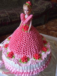 a cake that looks like a barbie doll on top of a table with pink flowers