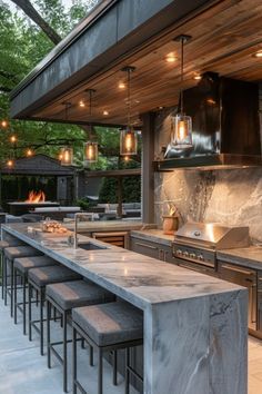 an outdoor kitchen with lots of counter space and lights hanging from the ceiling above it