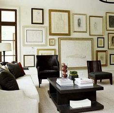 a living room filled with furniture and framed pictures on the wall above it's coffee table