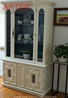 a white china cabinet with glass doors on the top and bottom, sitting in a living room