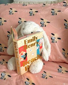 a white stuffed animal sitting on top of a bed next to a pink comforter