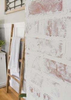 a white brick wall in the corner of a room with a ladder and towel rack