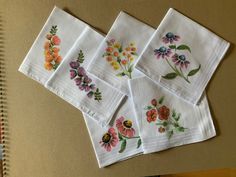 six embroidered napkins with flowers on them