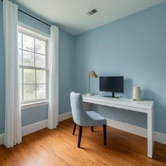 a white desk with a computer on top of it in front of a large window