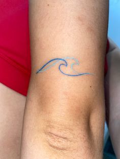 a woman's arm with a tattoo on it that has a wave in the middle