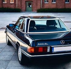 a black mercedes parked in front of a brick building