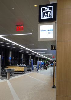 an airport terminal with luggage and signs on the wall above it that read, united club