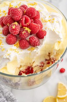 a dessert with whipped cream, raspberries and lemons on top in a glass bowl