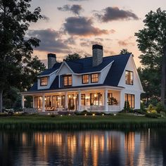 a large white house sitting on top of a lush green field next to a lake