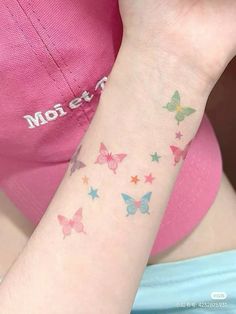 a person with a small tattoo on their arm and wrist is wearing a pink t - shirt