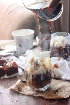 someone is pouring ice cream on top of some brownies in glass mugs and napkins