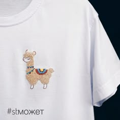 a white t - shirt with an embroidered llama on it