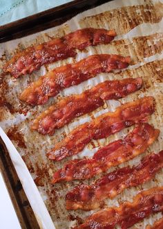 bacon strips are lined up on a baking sheet