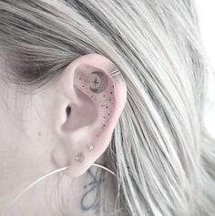 a close up of a person's ear with small dots on it and a cross behind the ear