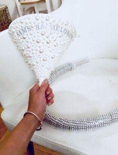 a woman is holding a white pillow with pearls on it