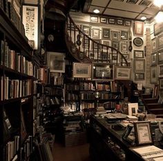 an old library with many books and pictures on the walls, along with a spiral staircase