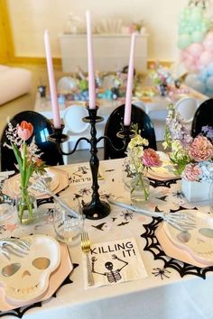 a table set for halloween dinner with skulls and flowers