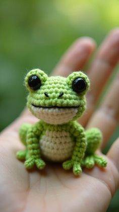 a small green frog sitting on top of a persons hand