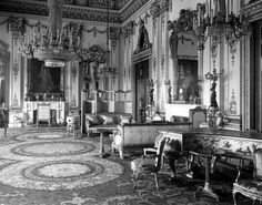 an old black and white photo of a living room with chandelier, couches, chairs and pictures on the wall