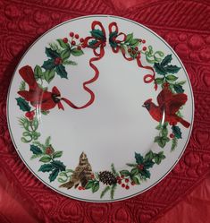 a white plate decorated with holly and red berries, pine cones, and birds on it