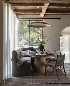 a living room with a couch, table and chairs in front of a large window