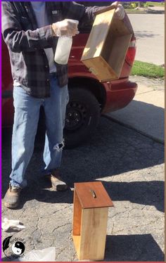 a man standing next to a red car holding an open box in front of him