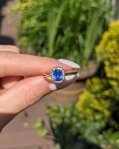 a woman's hand holding an engagement ring with a blue stone