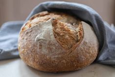 a loaf of bread sitting on top of a table next to a blue cloth covered bag