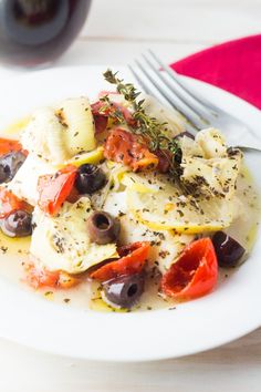 a white plate topped with pasta and olives