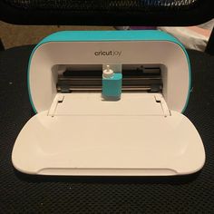 a small machine sitting on top of a black table next to a computer chair with a blue and white cover