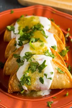 two quesadillas on an orange plate topped with sour cream and cilantro