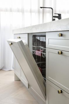 an open dishwasher door in a kitchen with white cabinets and countertop space