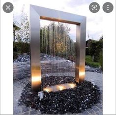 an outdoor fountain with lights on it and rocks in the ground next to each other