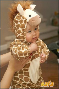 a baby in a giraffe costume is looking at the camera while holding it's head