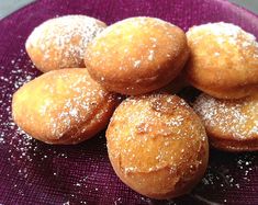 a purple plate topped with donuts covered in powdered sugar