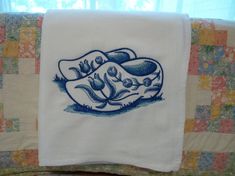 a blue and white dish towel sitting on top of a bed next to a window