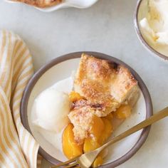 a slice of peach cobbler on a plate with ice cream and a fork next to it