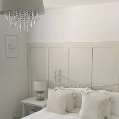 a white bed topped with pillows and a chandelier