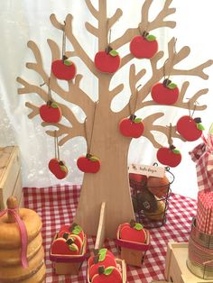 an apple tree with apples hanging from it's branches and some other items on the table